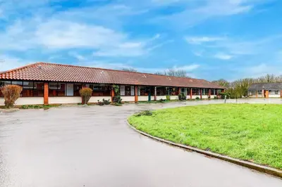 a large building with a grass field in front of it at The Rivenhall Hotel in Witham, Chelmsford in Witham