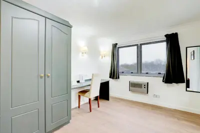 a room with a desk and a door and a chair at The Rivenhall Hotel in Witham, Chelmsford in Witham