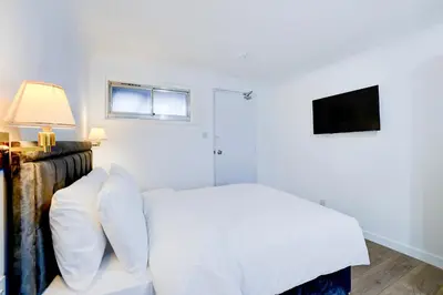a white bedroom with a bed and a television at The Rivenhall Hotel in Witham, Chelmsford in Witham