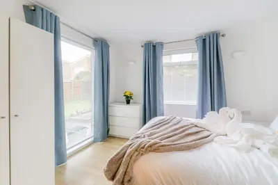 a bedroom with a bed with blue curtains and a window at Tiger House Stevenage 5 Bed 4 Bath Group Bookings in Stevenage