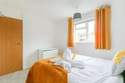 a bedroom with a bed with white sheets and a window at Tiger House Stevenage 5 Bed 4 Bath Group Bookings in Stevenage