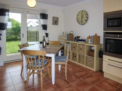 a kitchen with a table and chairs and a clock on the wall at 3 Hazlewood in Aldringham