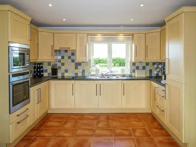 a large kitchen with wooden cabinets and a window at 3 Hazlewood in Aldringham