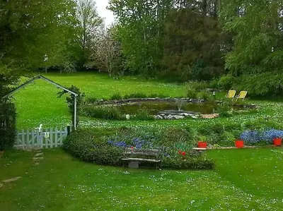 a garden with a pond and flowers in a yard at Owlhoot Annexe in Sudbury