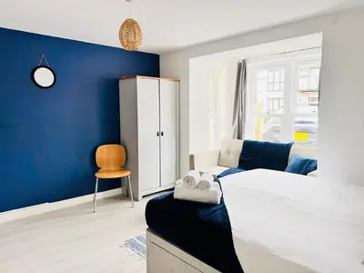 a bedroom with a blue wall and a bed and a chair at Stylish Cambridge Apartment with Garden in Cambridge