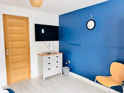 a room with a blue wall with a dresser and a clock at Stylish Cambridge Apartment with Garden in Cambridge