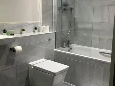 a bathroom with a toilet and a shower and a sink at Spacious, bright 2 bed flat with 1 S/king bed. in Brentwood