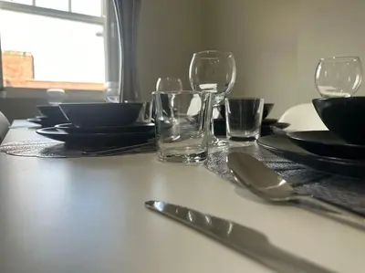 a table with glasses and plates and utensils on it at Spacious, bright 2 bed flat with 1 S/king bed. in Brentwood