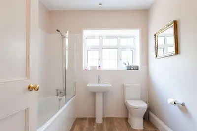 a bathroom with a sink and a toilet and a window at FIRS Sleeps 15 Stunning country house with hot tub in Sudbourne