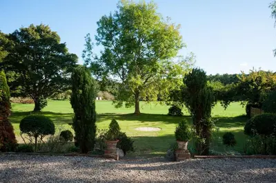 a garden with trees and shrubs in a field at FIRS Sleeps 15 Stunning country house with hot tub in Sudbourne