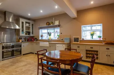 a large kitchen with a wooden table and a table and chairs at FIRS Sleeps 15 Stunning country house with hot tub in Sudbourne
