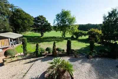 a garden with trees and bushes in a field at FIRS Sleeps 15 Stunning country house with hot tub in Sudbourne
