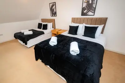 a bedroom with two beds with black and white sheets at Group Retreat Perfect Home with FREE Parking in Freston