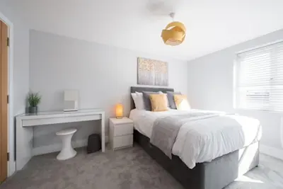 a white bedroom with a bed and a desk at Beautiful, Spacious 1 bed flat in Brentwood