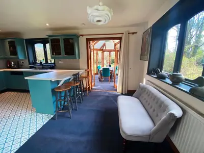 a kitchen with a couch and a bar with chairs at Rivendell in Diss