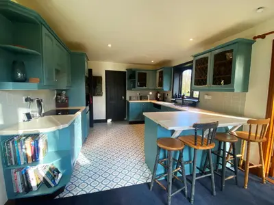 a kitchen with blue cabinets and bar stools at Rivendell in Diss