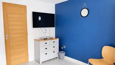 a room with a blue wall and a dresser and a mirror at Cambridge - Modern 4-BR Home with Gardens & Wi-Fi in Cambridge