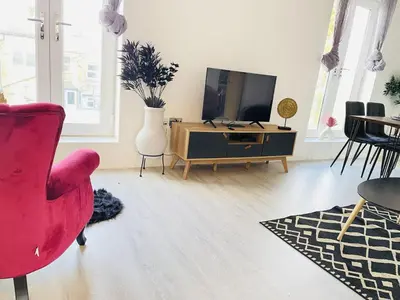a living room with a red chair and a tv at Cambridge - Modern 4-BR Home with Gardens & Wi-Fi in Cambridge
