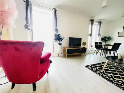 a living room with a red chair and a table at Cambridge - Modern 4-BR Home with Gardens & Wi-Fi in Cambridge