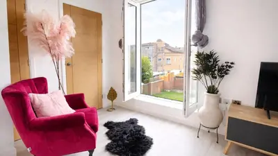 a black dog sitting in a living room with a chair and a window at Cambridge - Modern 4-BR Home with Gardens & Wi-Fi in Cambridge