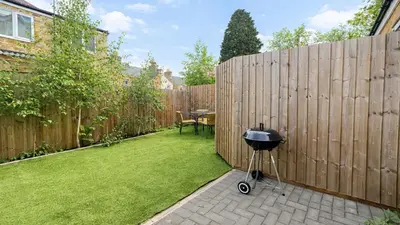 a small backyard with a fence and a grill at Cambridge - Modern 4-BR Home with Gardens & Wi-Fi in Cambridge