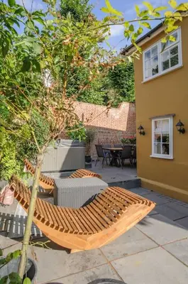 a patio with a wooden bench and a table at The Famous Harry Potter House, Hot Tub, Cinema Room, Sky TV in Saffron Walden