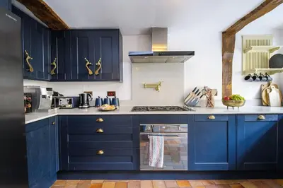 a kitchen with blue cabinets and a stove at Luxury 3 Bed Manor House With Hot Tub, Cinema Room, Sky TV in Saffron Walden