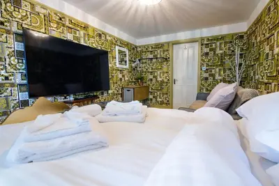 a bedroom with a large white bed and a tv at Deluxe 1 Bed Versace Hot Tub Sky TV Cinema Screen in Great Sampford