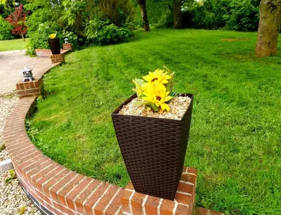 a planter with a yellow flower in a brick path at Deluxe 1 Bed Versace Hot Tub Sky TV Cinema Screen in Great Sampford
