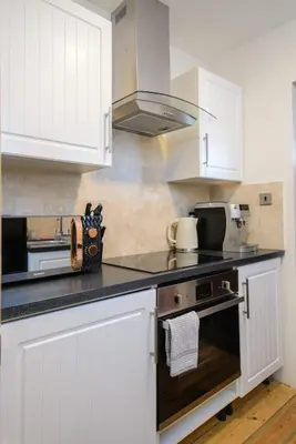 a kitchen with white cabinets and a stove top oven at Deluxe 1 Bed Versace Hot Tub Sky TV Cinema Screen in Great Sampford