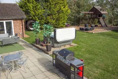 a grill and a large screen tv in a yard at Deluxe 1 Bed Versace Hot Tub Sky TV Cinema Screen in Great Sampford