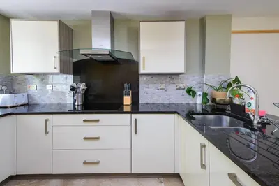 a kitchen with white cabinets and a sink at Deluxe 2 or 3 bed Cinema Games Room Pool Table Hot Tub in Great Sampford