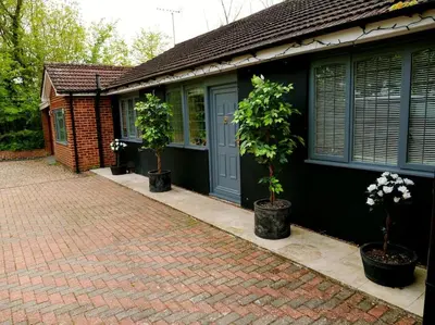 a house with two potted trees in front of it at Deluxe 2 or 3 bed Cinema Games Room Pool Table Hot Tub in Great Sampford