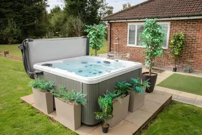 a hot tub in a yard with potted plants at Deluxe 2 or 3 bed Cinema Games Room Pool Table Hot Tub in Great Sampford