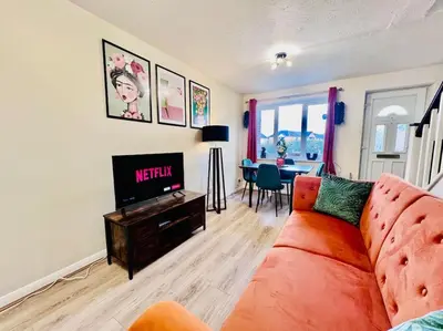 a living room with a orange couch and a television at Hidden Gem in Chelmsford by Artisan Stays I Weekly or Monthly Stay Offer I Free Parking I Sleeps 5 in Chelmsford