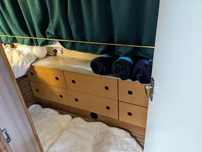 a bedroom with a wooden dresser with a green curtain at New Horizon - A beautiful boat very conveniently located in Chelmsford City in Chelmsford