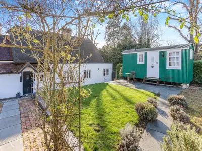 a garden with a caravan and a house at Malting Cottage in Much Hadham