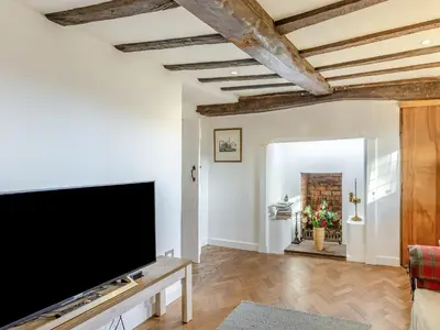 a living room with a large flat screen tv at Malting Cottage in Much Hadham
