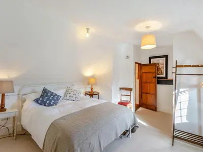 a bedroom with a white bed with blue pillows at Malting Cottage in Much Hadham