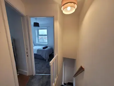 a hallway with a room with a bed and a window at Little Oaks House - Historic Charm & Modern Comfort in Colchester by Catchpole Stays in Colchester