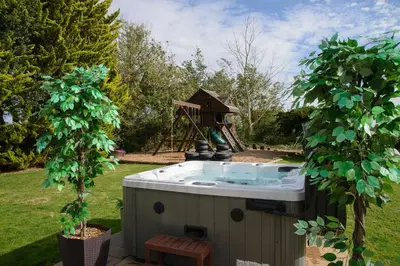 a hot tub in a garden with a gazebo at Deluxe 2 Bed Versace HotTub SkyTV in Saffron Walden