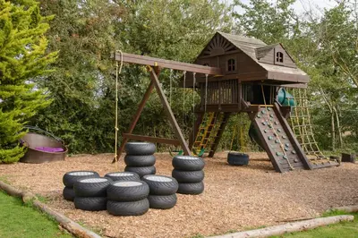 a playground with a tree house and some tires at Deluxe 2 Bed Versace HotTub SkyTV in Saffron Walden
