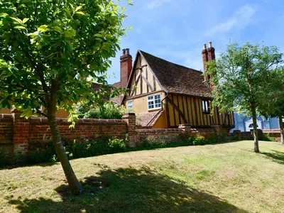 a house with a fence and a tree in front of it at Executive Suite with Private Hot Tub SkyTV in Saffron Walden