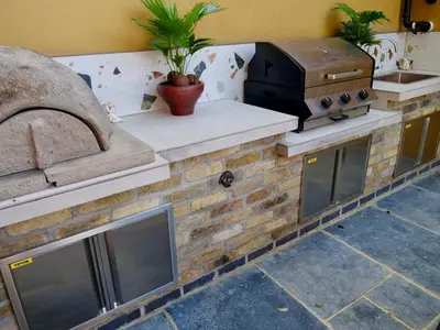 an outdoor kitchen with a grill and a pizza oven at Executive Suite with Private Hot Tub SkyTV in Saffron Walden