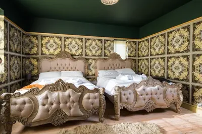 two beds in a bedroom with ornate wallpaper at Deluxe 2 3 Bed HotTub SkyTV in Saffron Walden