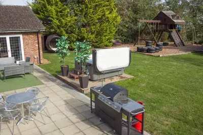 a backyard with a big screen tv and a grill at Deluxe 1 Bed Versace HotTub SkyTV in Saffron Walden