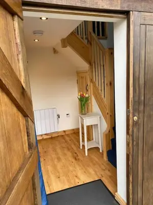 an open hallway with a table and a vase of flowers at The Cartlodge, Debenham in Debenham