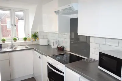 a white kitchen with a sink and a stove at Tulip Place in Chelmsford