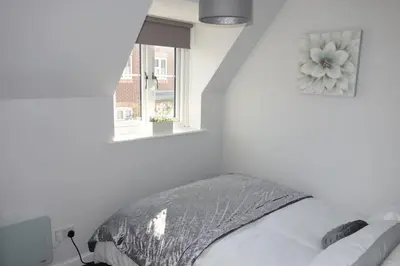 a white bedroom with a bed and a window at Tulip Place in Chelmsford