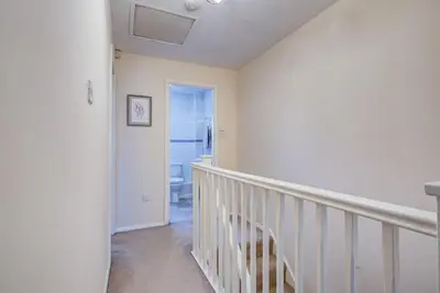 a white hallway with a staircase leading to a bathroom at Comfortable 3 bed house in Chelmsford in Chelmsford